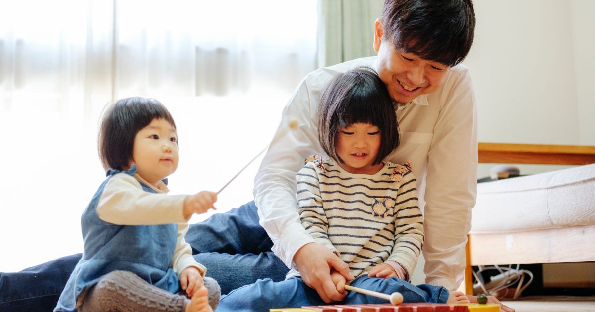 おもちゃの木琴で遊ぶ父と姉妹