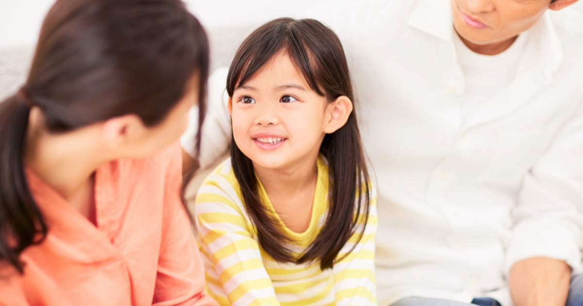 両親に囲まれ、笑顔で話を聞く女の子の表情