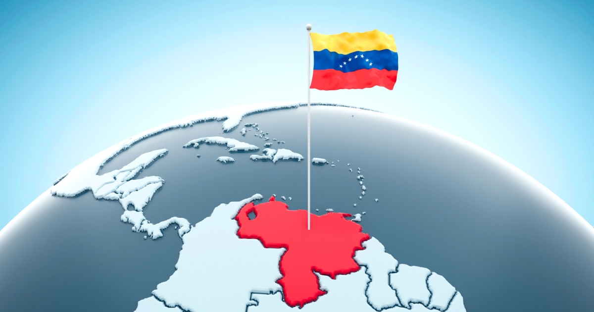 地球儀の北部南米付近で、ベネズエラの領域が赤く強調され、上にベネズエラ国旗が立てられているイメージ