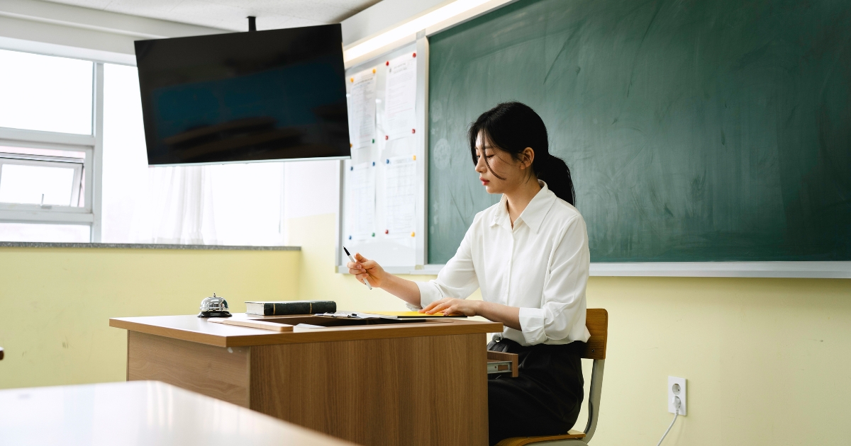 机の上で作業する小学校の先生