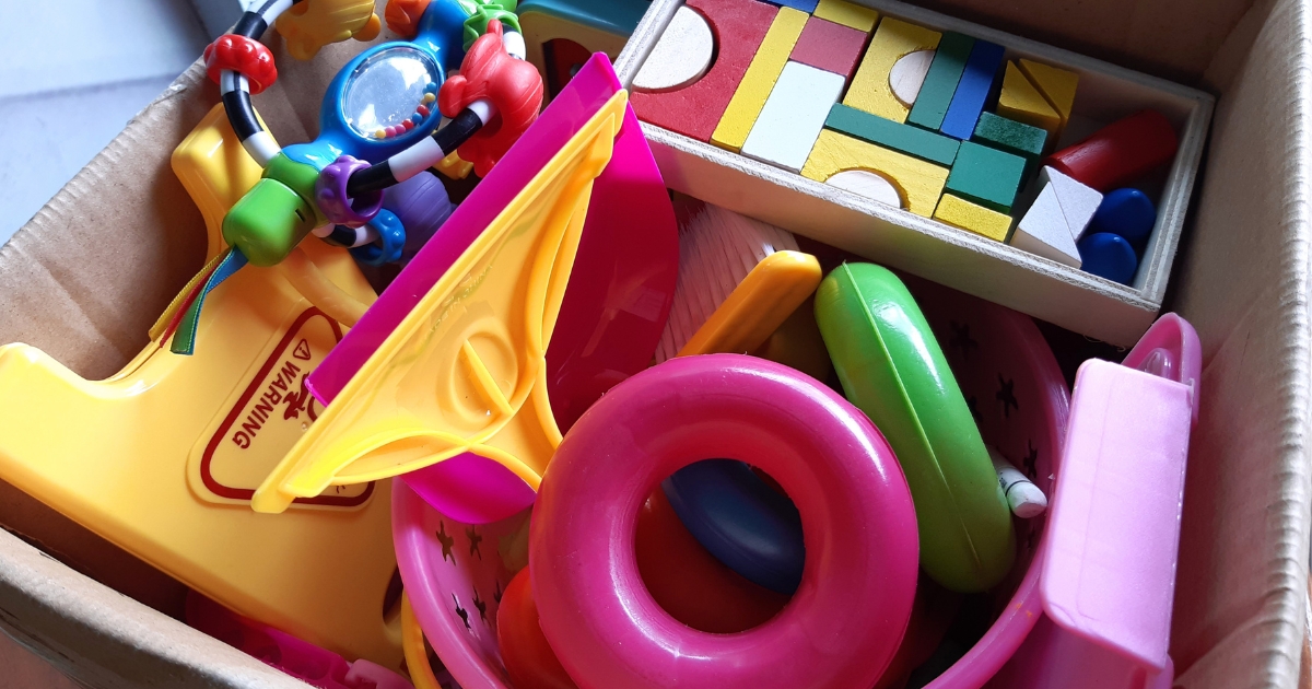 段ボール箱のなかに無造作に詰め込まれた、色や形がのカラフルなプラスチックおもちゃや積み木