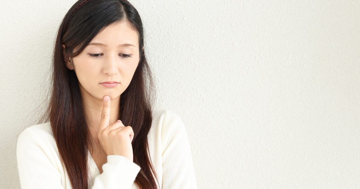 手をあごに当てて、伏し目がちに悩んでいる女性