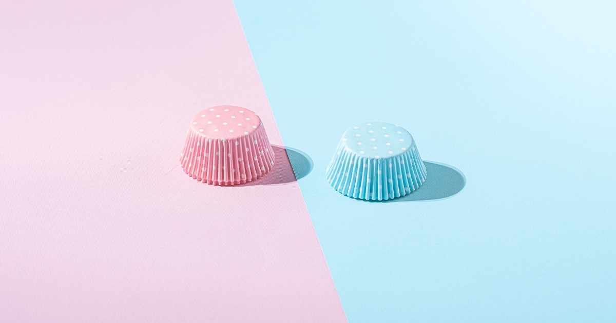 性別による色の固定観念を連想させる、ピンクと水色に分かれた背景と2つの水玉模様の紙カップ