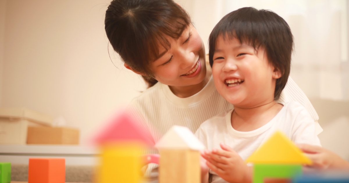 笑顔で寄り添う母親と、楽しそうに笑う幼い子ども。