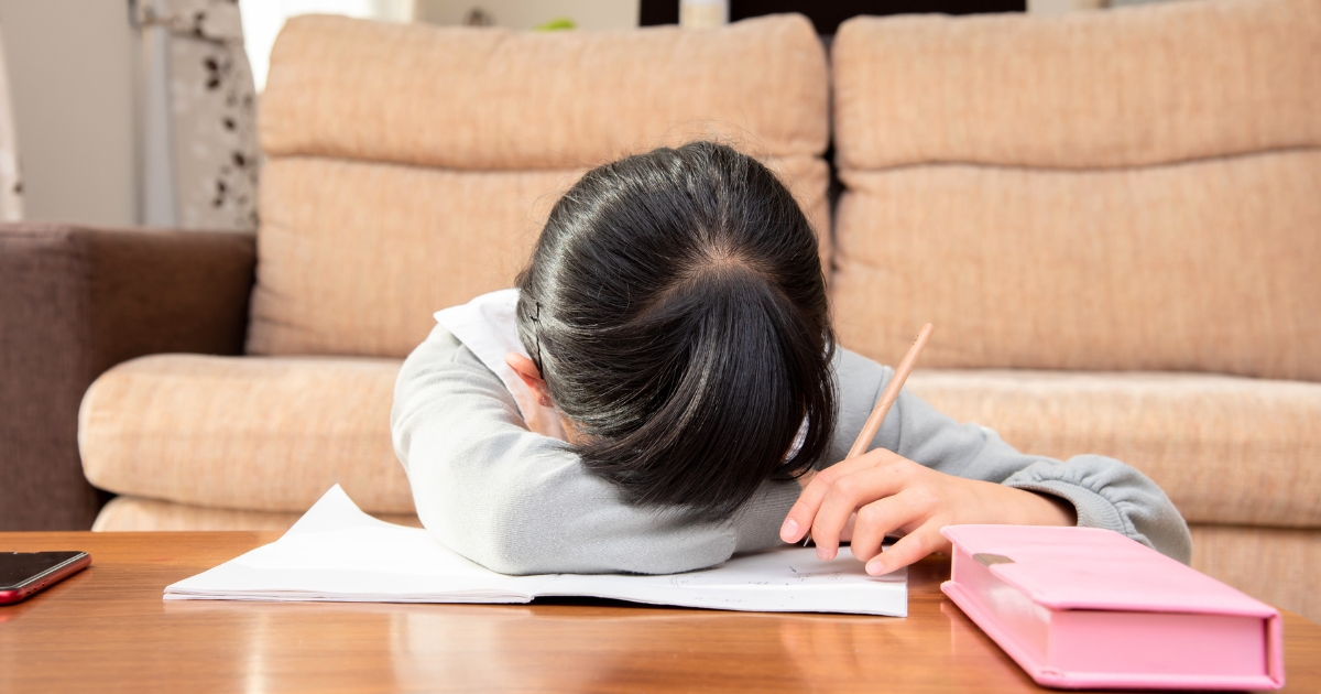 鉛筆を持ったままノートの上に突っ伏し、疲れ切った様子の女の子