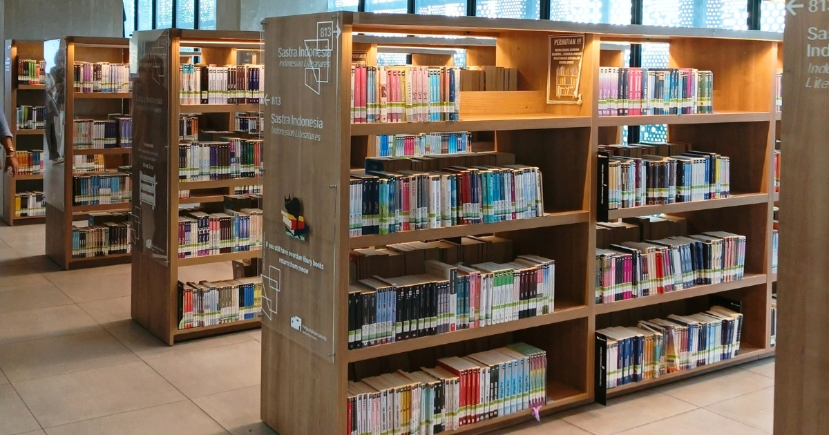 温かみのある木製の書架に本がずらりと並ぶ、明るく開放的な図書館の風景