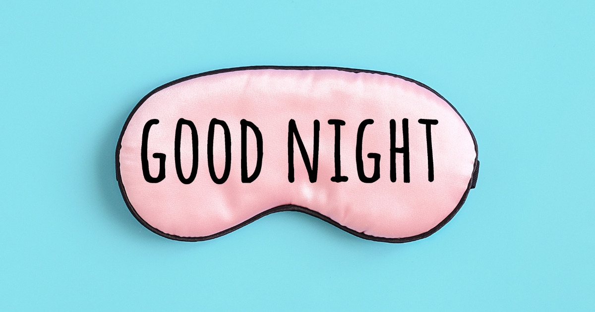 水色の背景に置かれた、GOOD NIGHTの黒いロゴが入った淡いピンク色のアイマスク