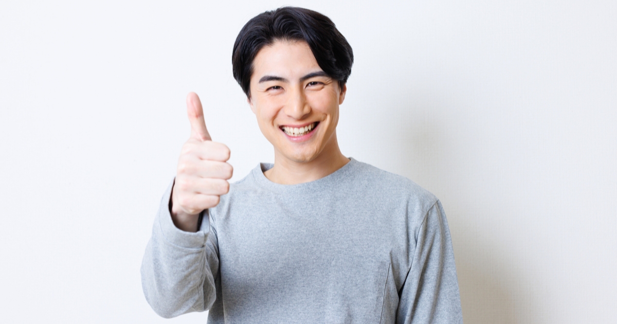 笑顔でサムズアップ(親指を立てる)ポーズをする男性
