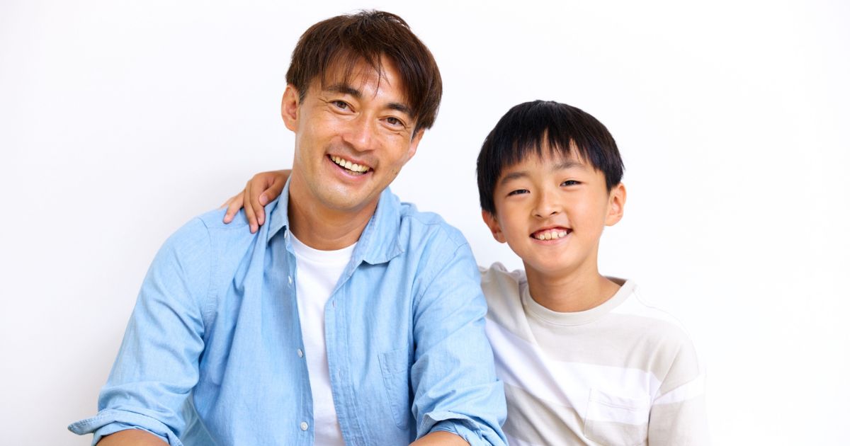 父親と息子が正面を向いて微笑んでいる様子