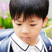 ランドセルを背負った男の子が下を見ている様子