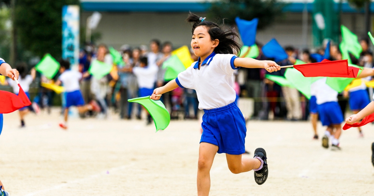 両手に旗を持って子どもが走る様子
