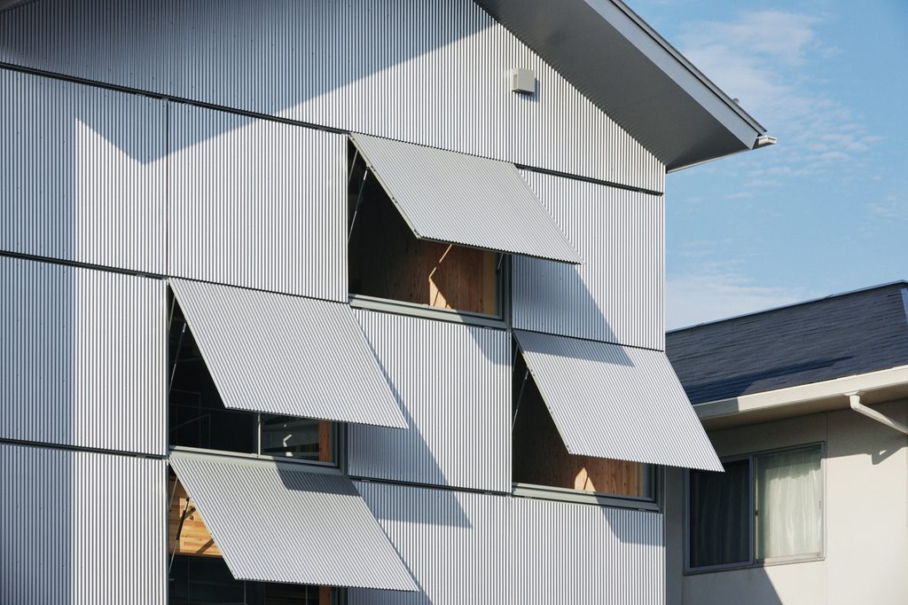 Awning windows tilted open on the corrugated metal façade
