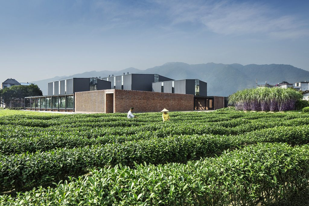 Brick service walls and steel factory roofs beside the fields