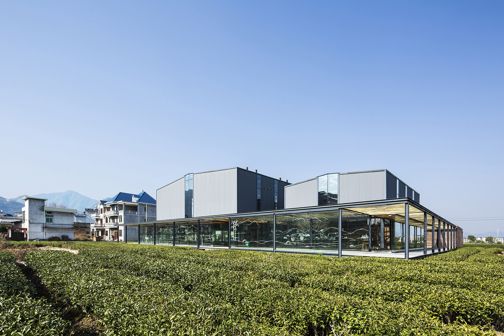 Glazed factory pavilions with shaded walkways facing the fields