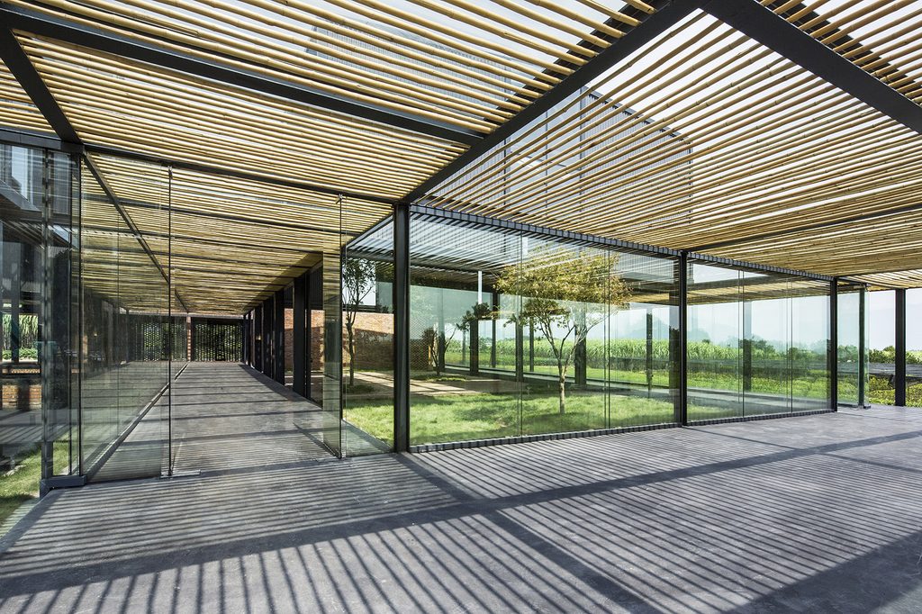Concrete walkway beneath bamboo slats along the factory glazing