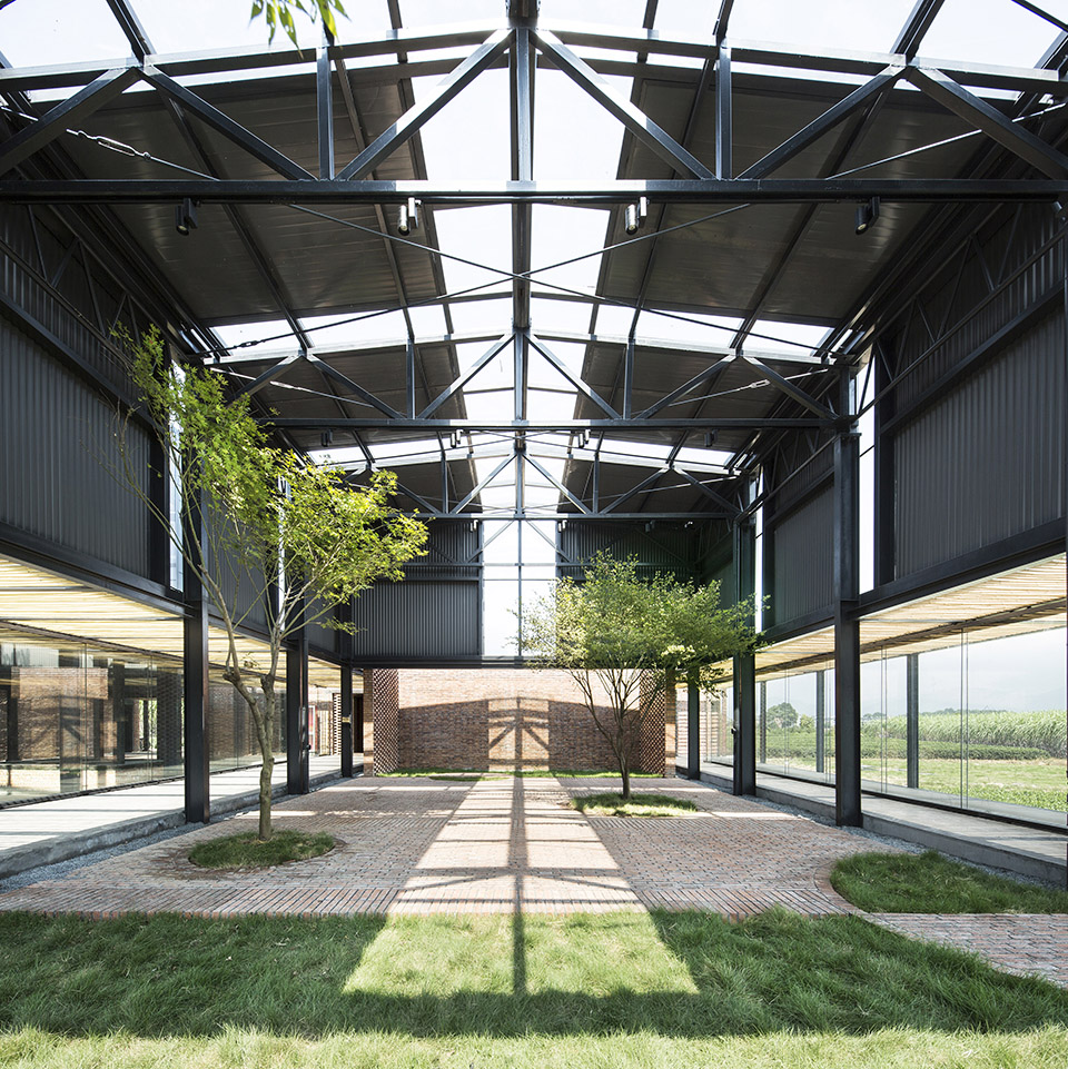 Open leisure hall with grass beneath a tall steel roof