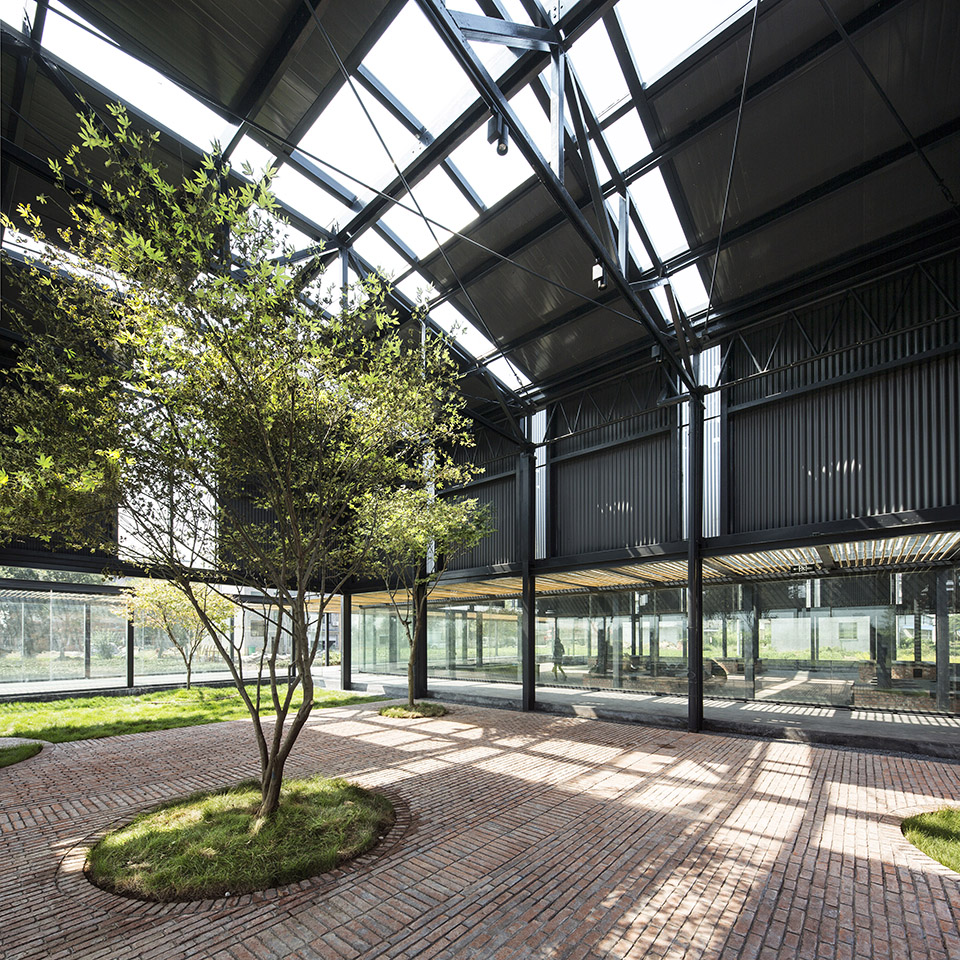Brick paving and trees inside the glazed leisure hall