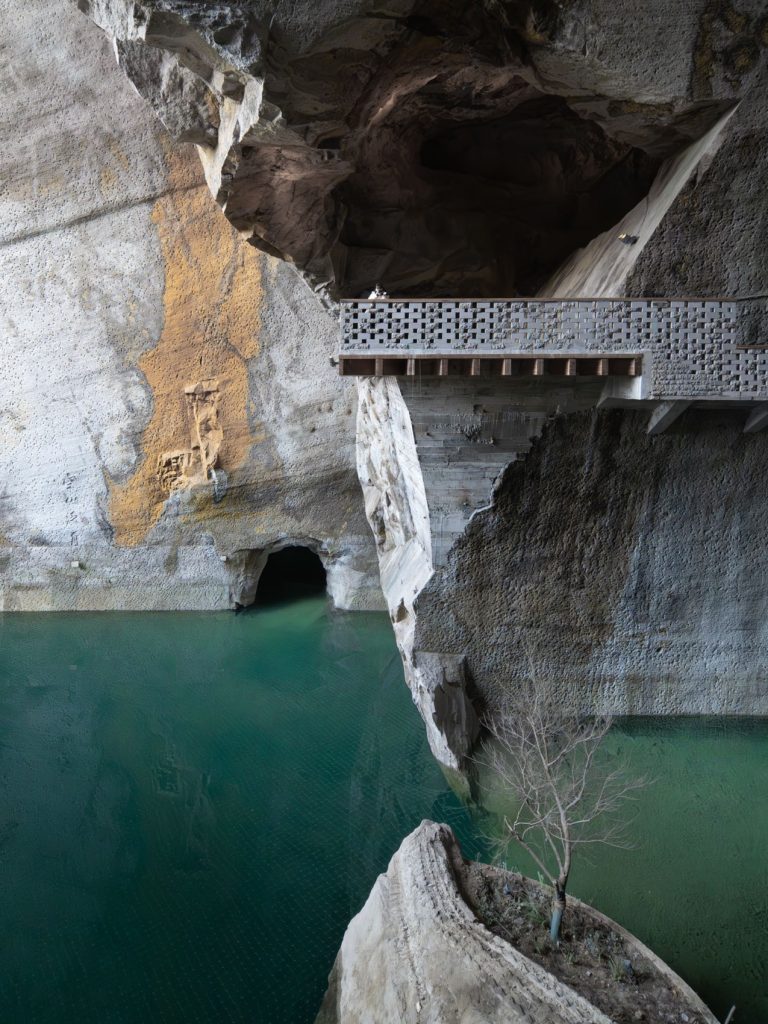 Walkway beside a narrow rock pillar and pool