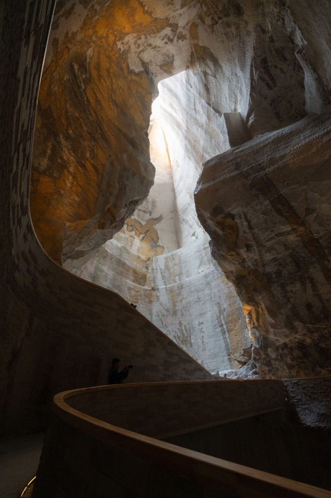 Curving timber handrail beneath a tall rock opening