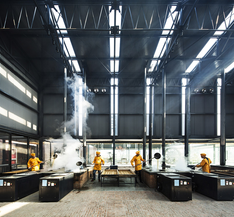 Workers tending sugar-making stoves beneath rooflights