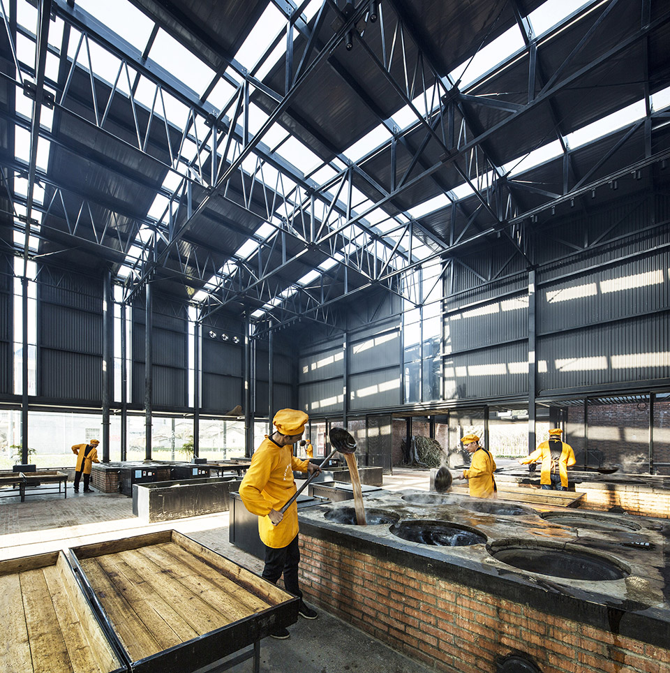 Worker beside cooking pots and cooling trays in the production hall