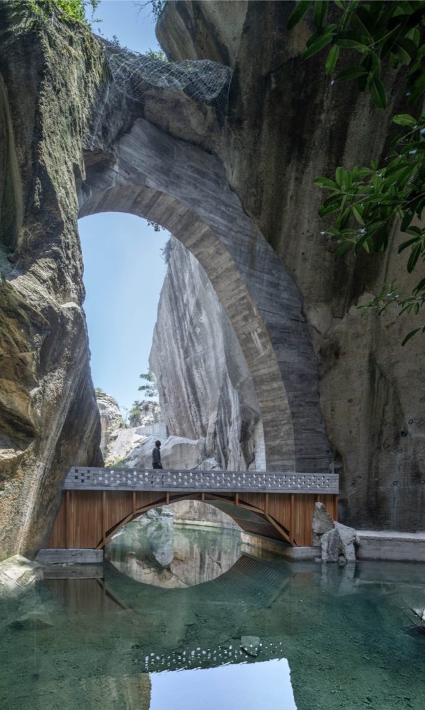 Timber arch bridge beneath an open rock arch