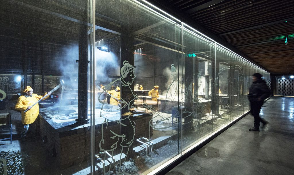Visitors observing sugar production through glass with white line artwork