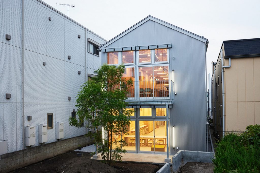 Rear façade lit at dusk, with a tree in the garden