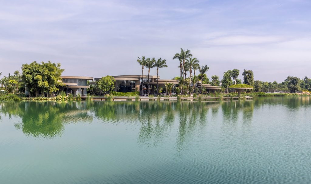 The clubhouse seen from across the lake, low among palms and trees