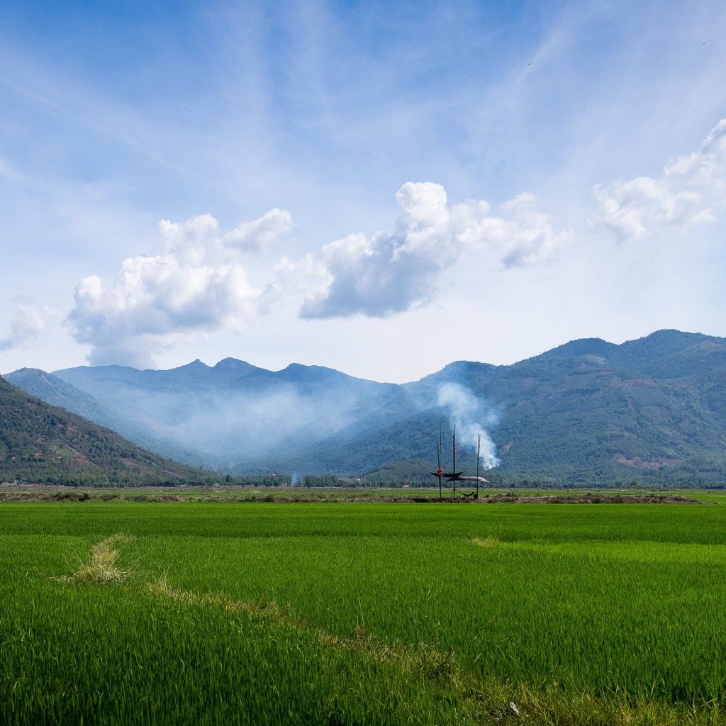 Rice fields and mountains with the hut near smoke from a field fire