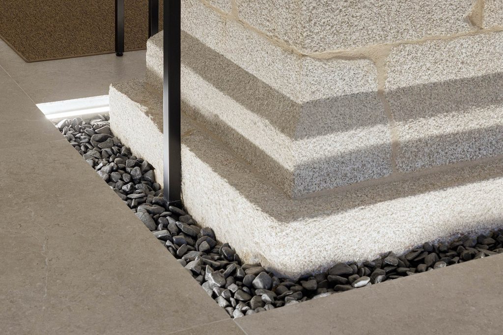 Stone column base bordered by dark pebbles