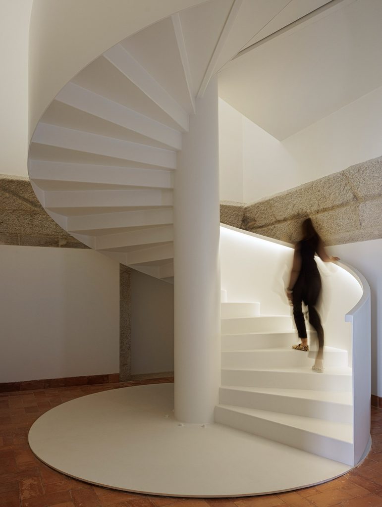 White spiral staircase beside historic masonry
