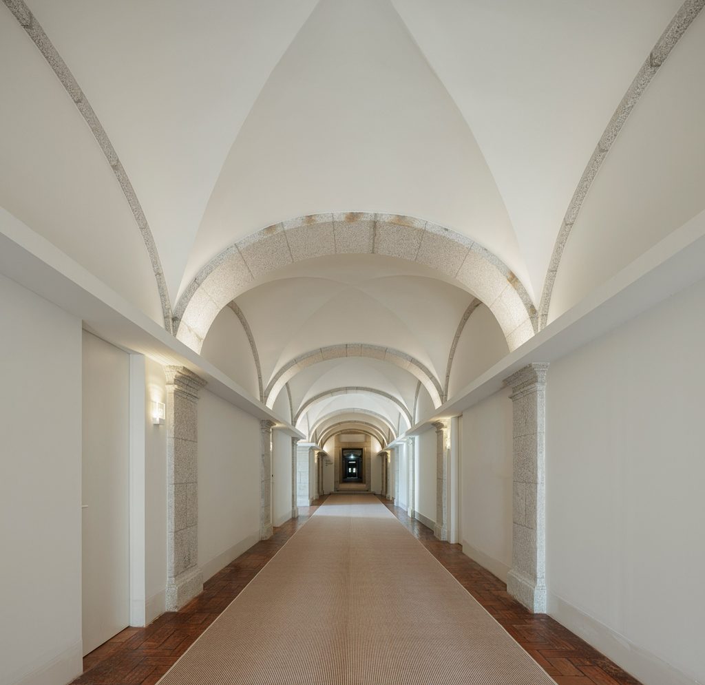 Long upper corridor beneath white vaults and stone arches