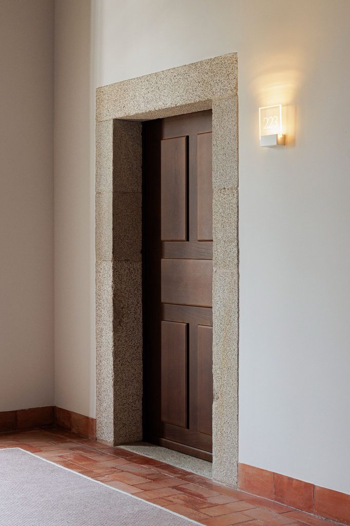 Timber door within a stone surround beside terracotta floor tiles