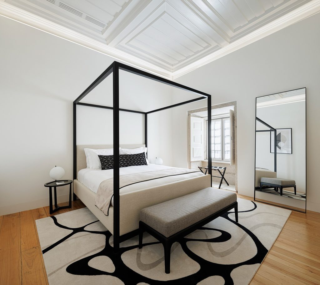 Guest room with a black four-poster bed and timber floor