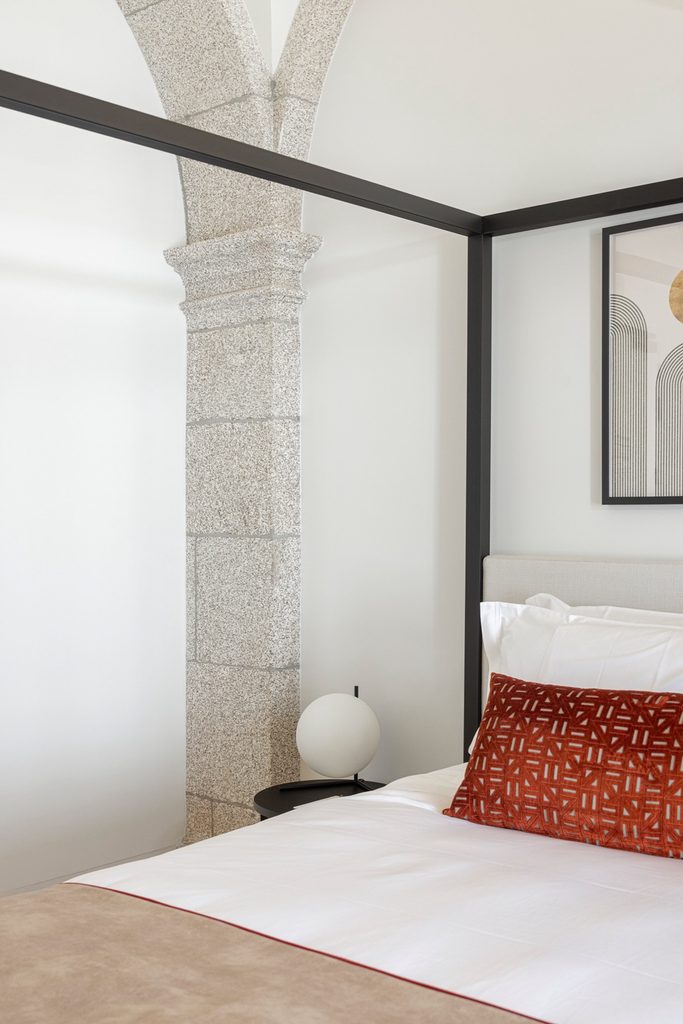 Four-poster bed beside a retained stone column