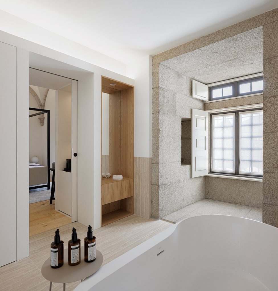 Freestanding bath beside a stone-framed window