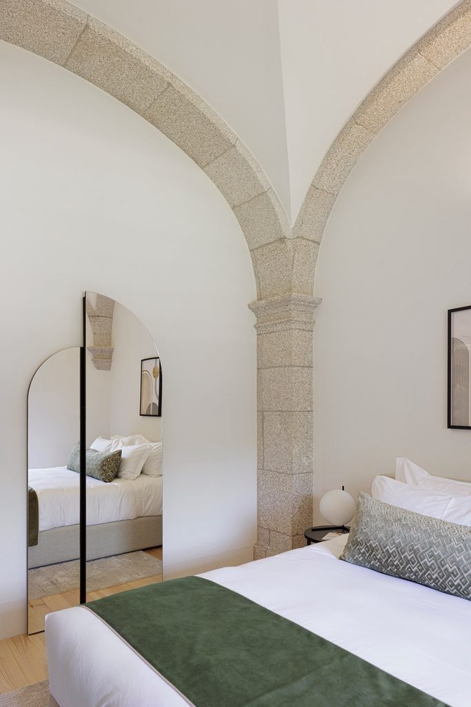 Bed and arched mirror beside a stone column