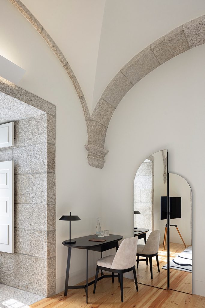 Guest room desk and mirror beneath stone vault ribs