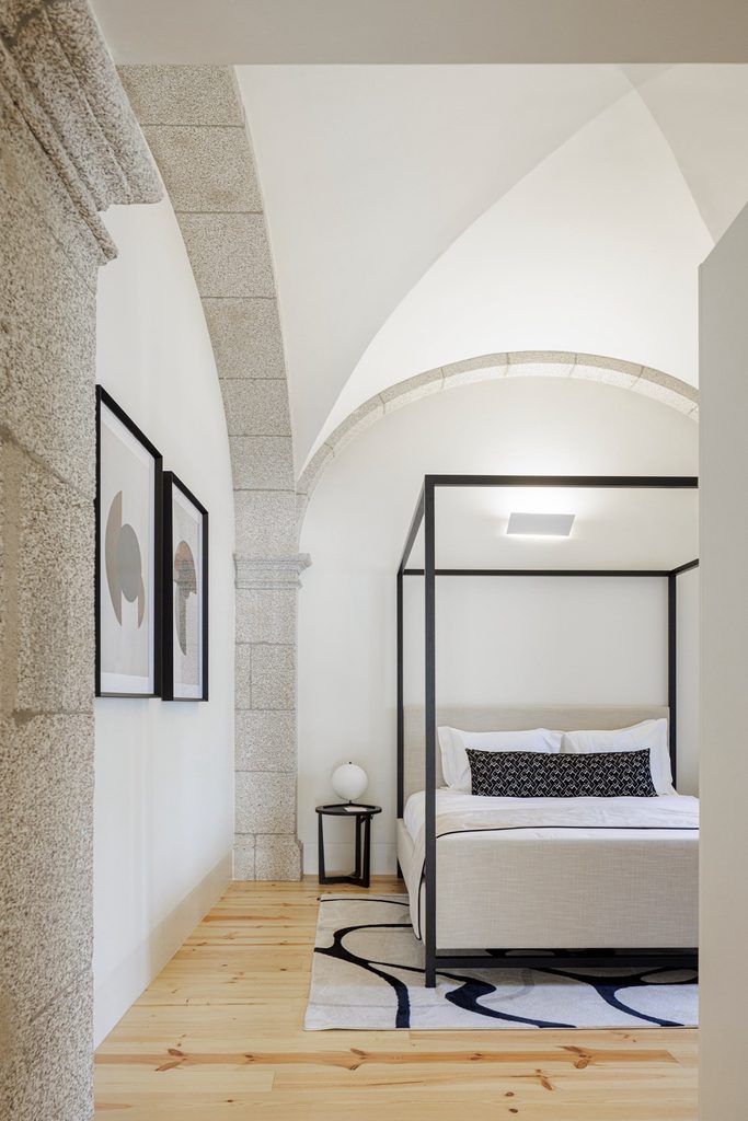 Four-poster bed beneath a white vault with stone ribs