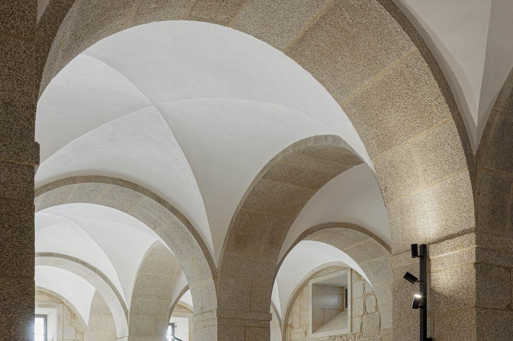 Intersecting stone arches beneath restored white vaults