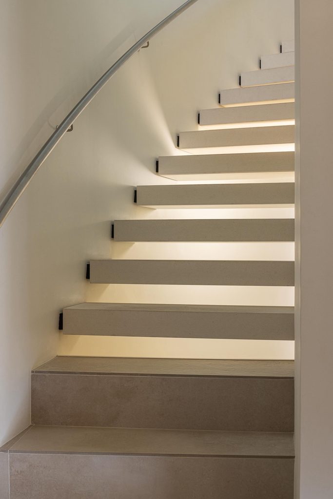 Stair treads with recessed lighting and a metal handrail
