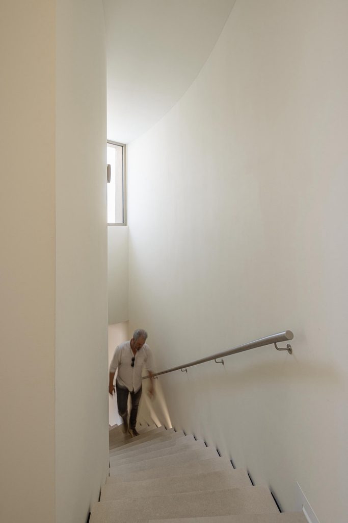 Staircase rising beside a tall white wall