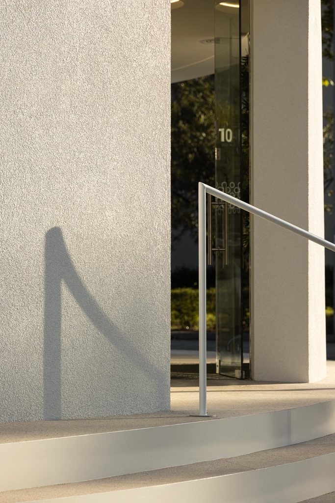 Glazed entrance and handrail beside the textured white wall