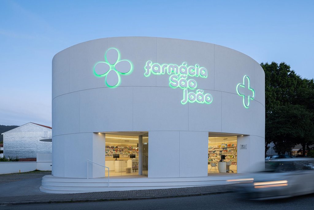 Pharmacy signage and shopfront illuminated at dusk
