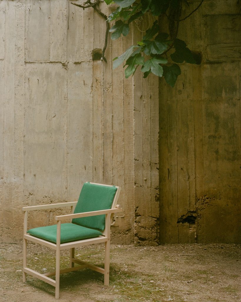 Parrot Chair in a courtyard against a tall concrete wall.