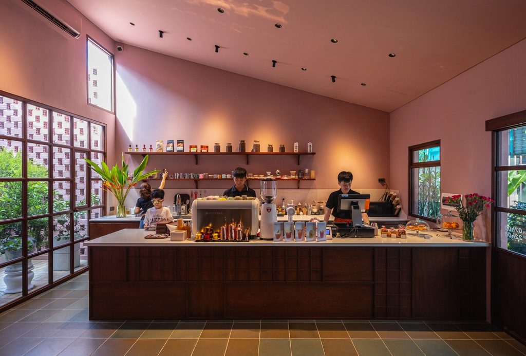 Cafe service counter beneath a high pink ceiling