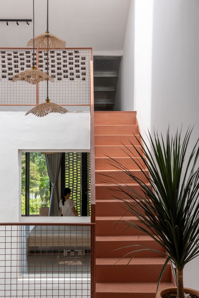Rust-coloured stair beside hanging woven lamps
