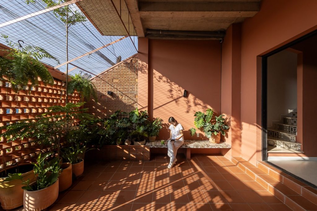 Sheltered balcony with greenery behind an open brick screen