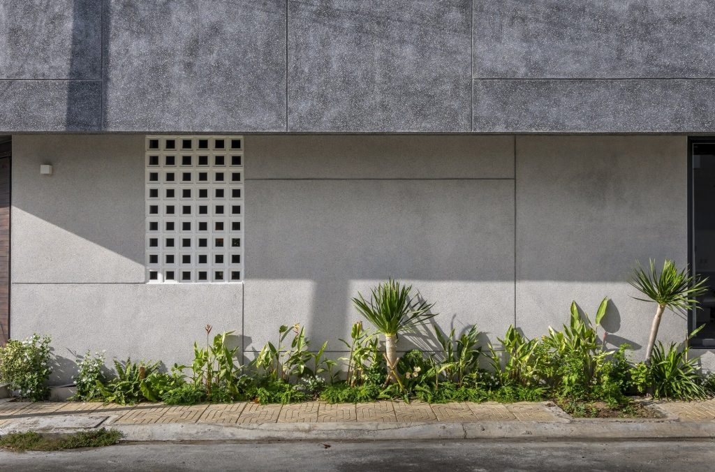 Facade joints and a small ventilation opening beside roadside greenery